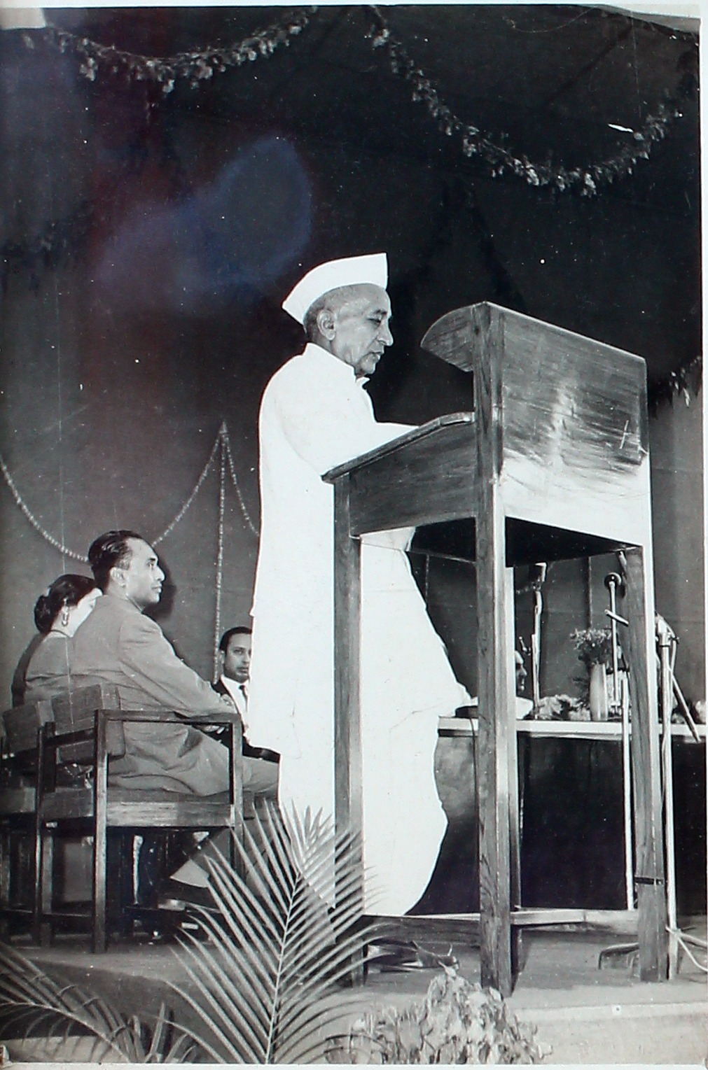 A man addressing a gathering from a wooden podium.