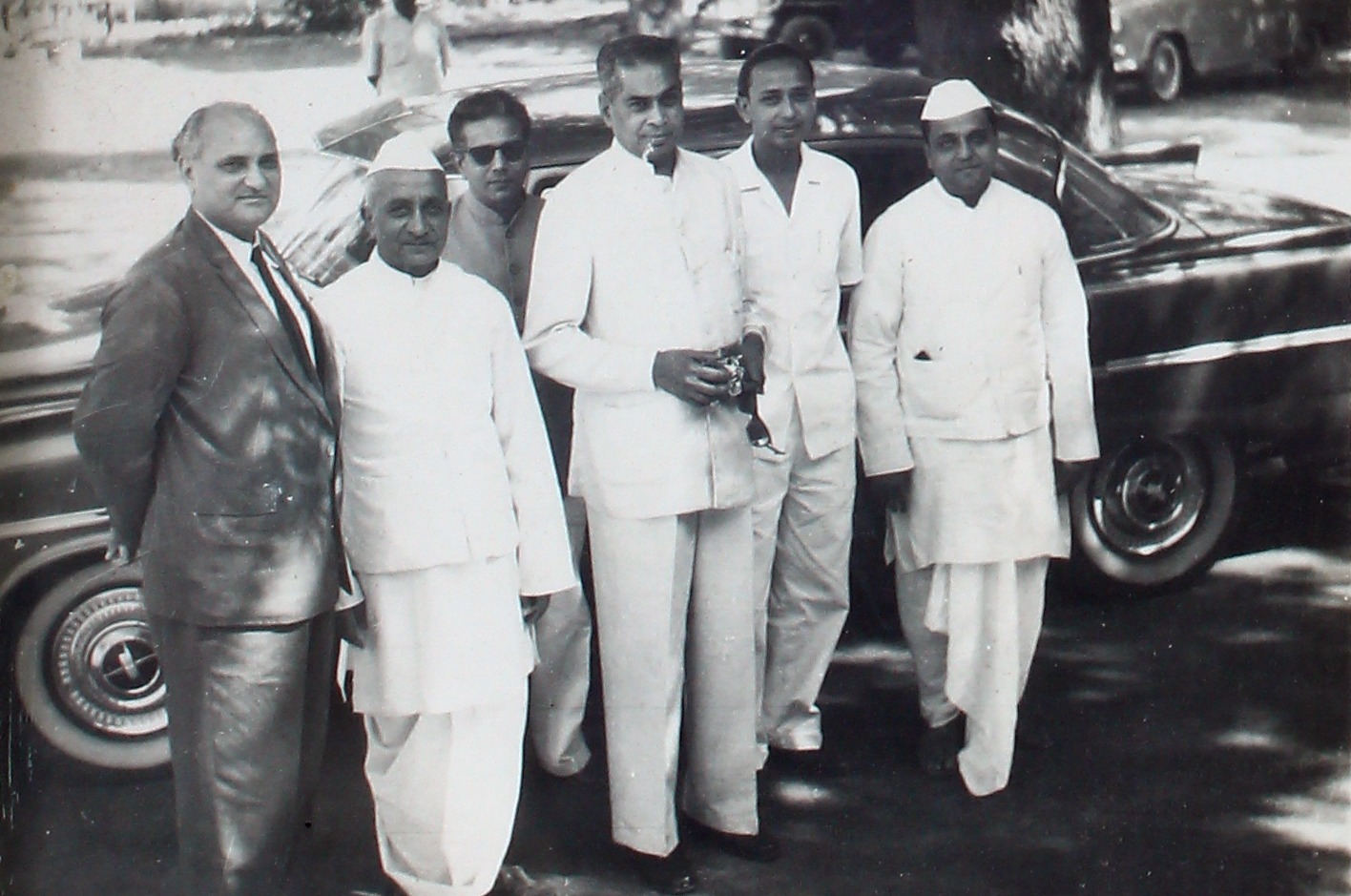 A group gathered beside a car on arrival at a function.